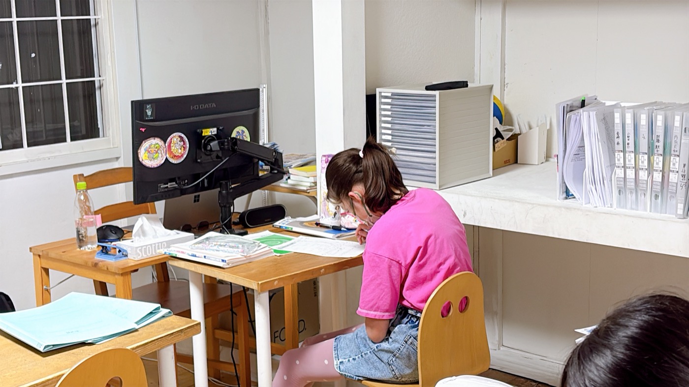 机に向かって一人で問題に取り組む小学生の後ろ姿